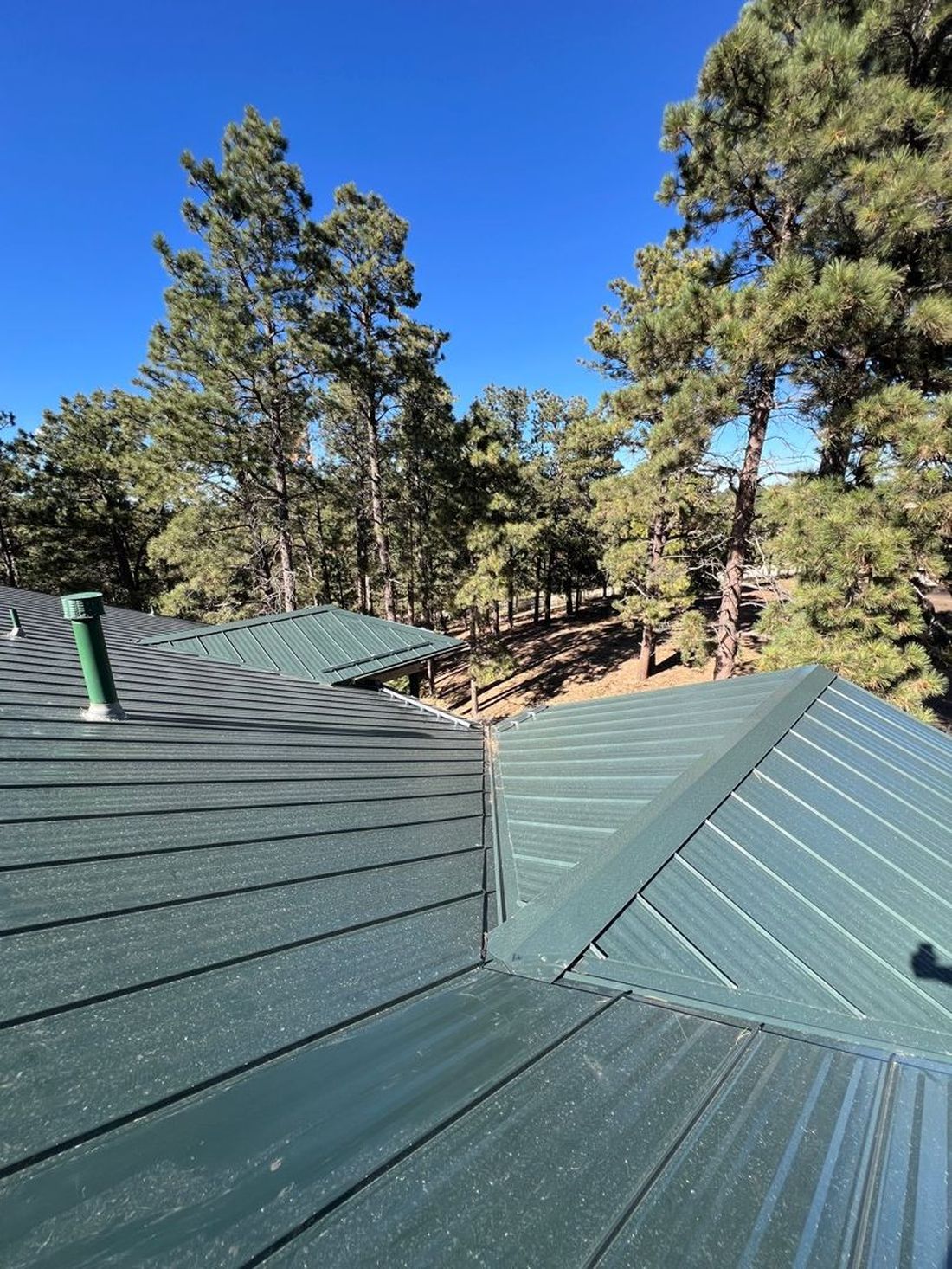 Certified roofer working on dark standing seam metal panels