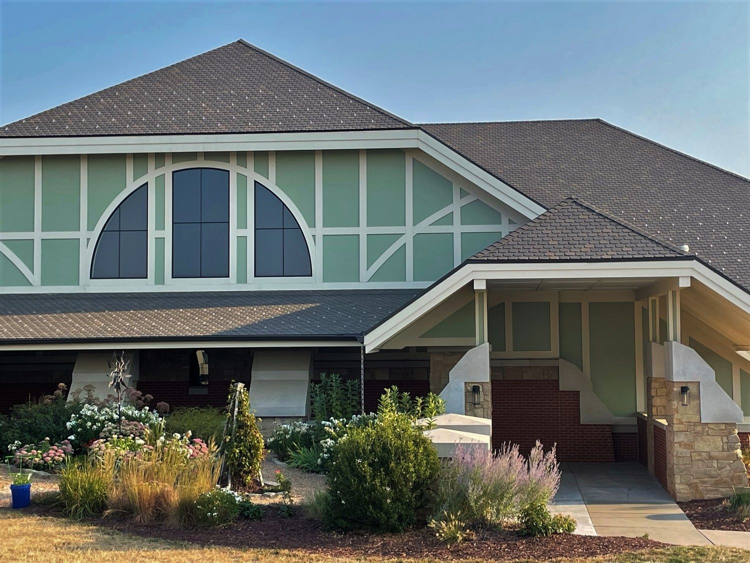Brown architectural shingle roof with multiple gables on a craftsman style building with green timbered gable and stone entry