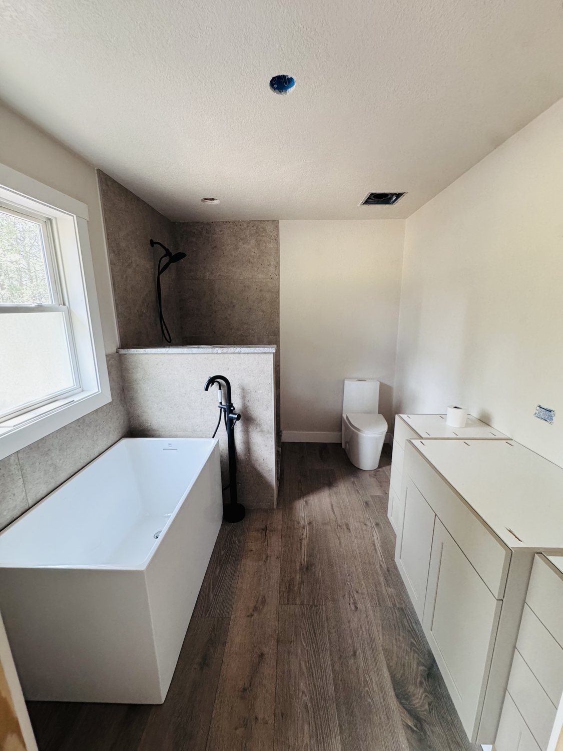Completed bathroom remodel with soaker tub, wood-look flooring, and custom vanity in Colorado Springs