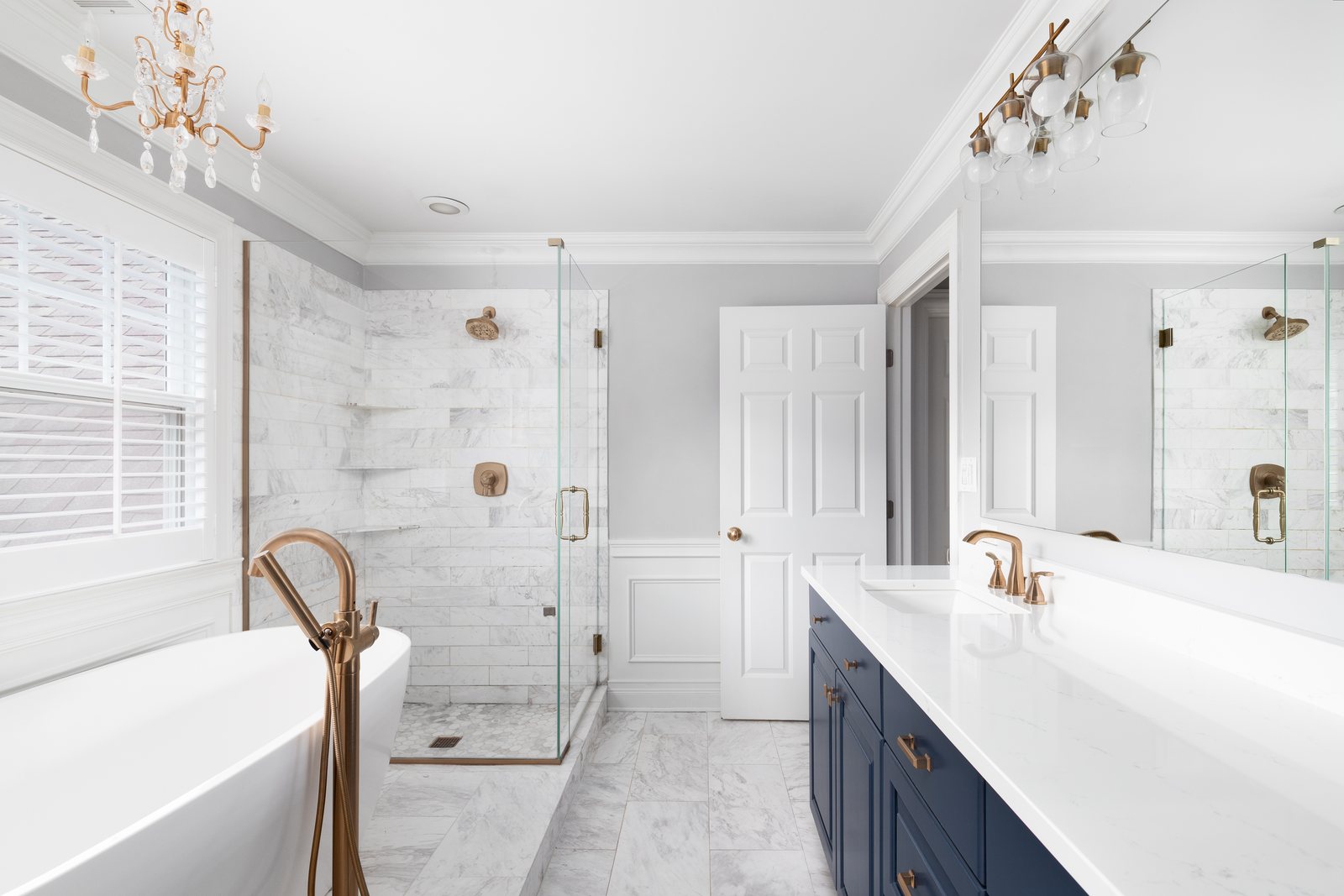 Luxury bathroom remodel with marble tile shower, freestanding tub, and navy vanity by Fixins in Colorado Springs