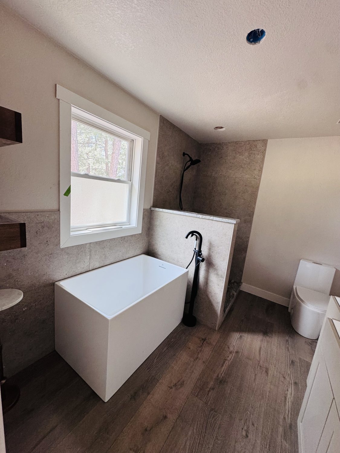 Finished bathroom remodel with freestanding soaker tub and stone tile shower in Colorado Springs by Fixins