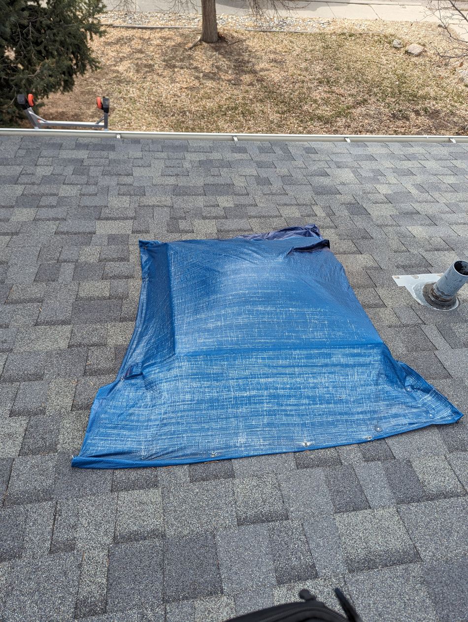 Fixins crew tarping around a skylight to seal a roof opening after storm damage in Colorado Springs
