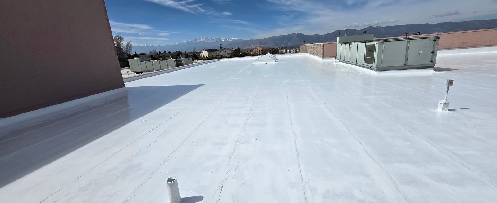 Fixins reflective roof coating on the flat commercial roof of the Briargate YMCA in Colorado Springs, Pikes Peak in the background