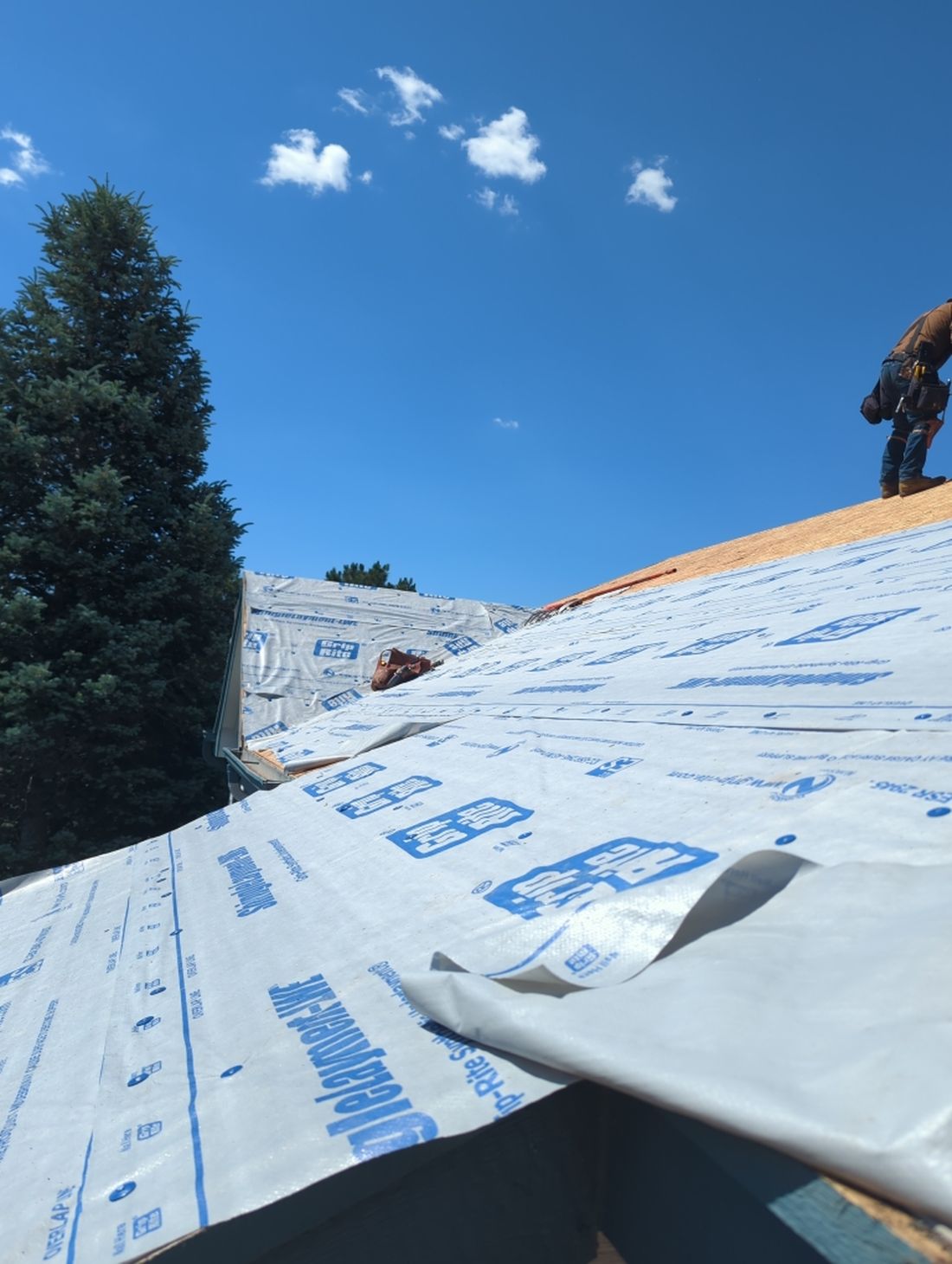 Fixins crew installing synthetic underlayment over new roof decking in Colorado Springs