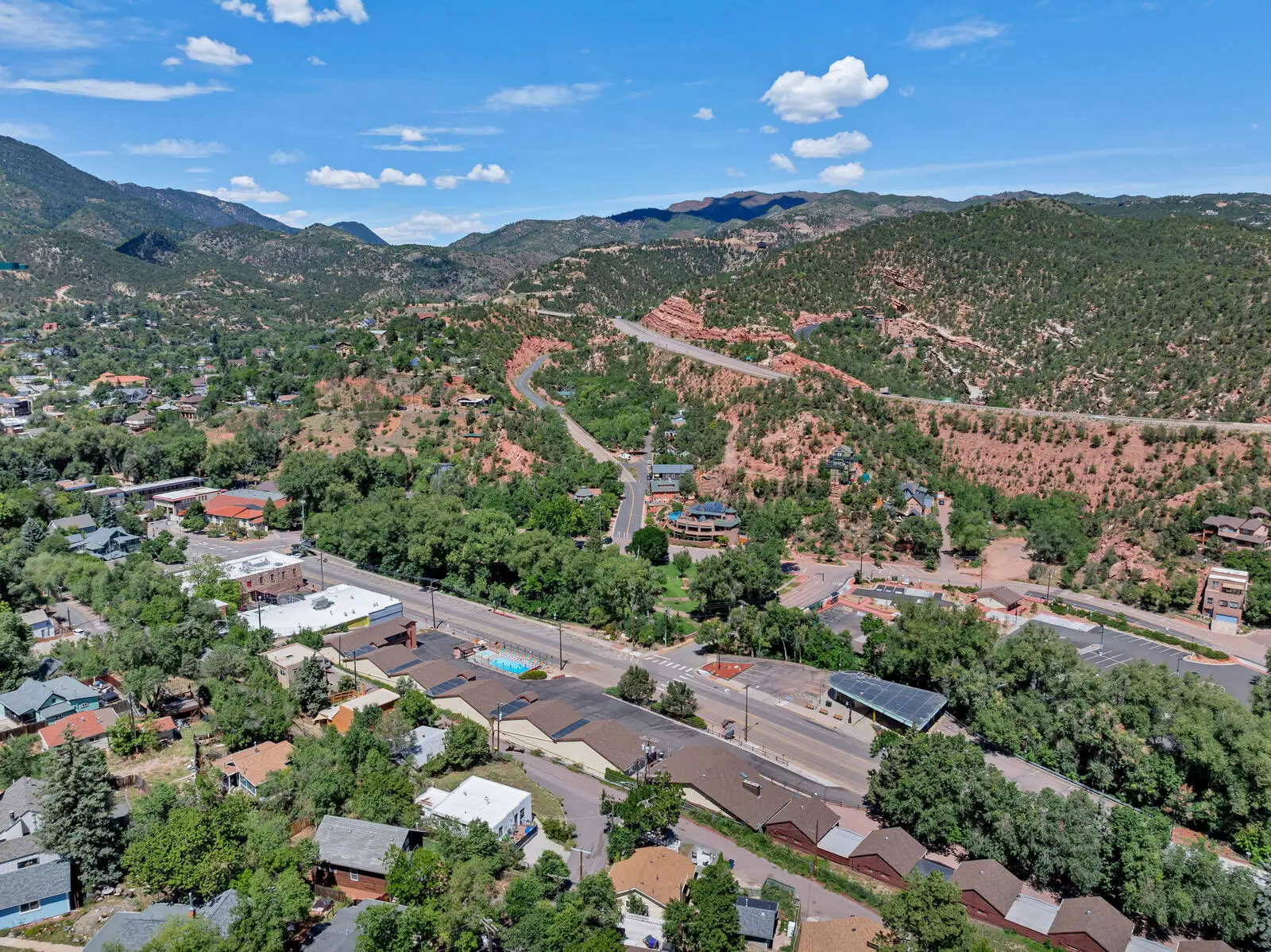 Aerial view of Manitou Springs with US Route 24 winding through the red rock hillside toward the Rocky Mountains