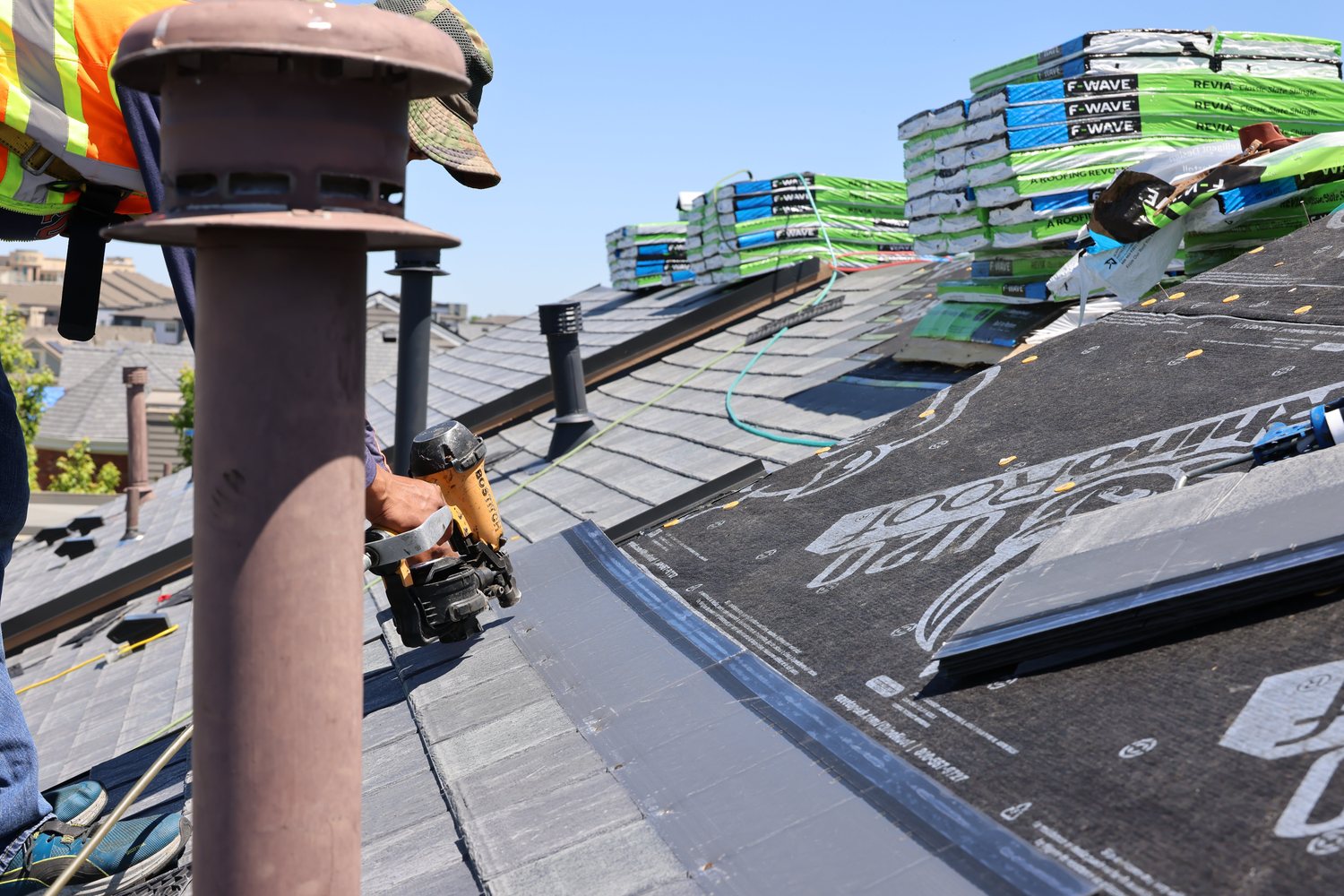 Fixins roofer nailing F-Wave REVIA synthetic slate shingles during a roof replacement