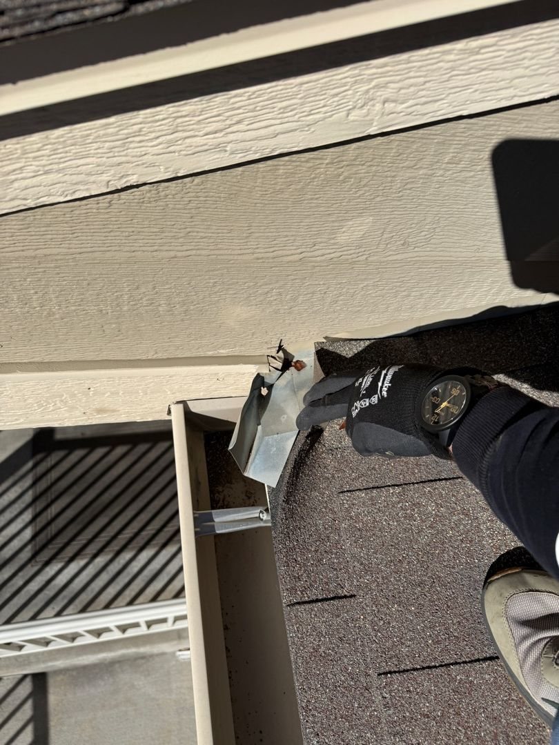 Fixins inspector checking flashing at a roof edge to pinpoint a leak in Colorado Springs